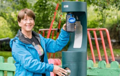 woman filling water bottle outdoors